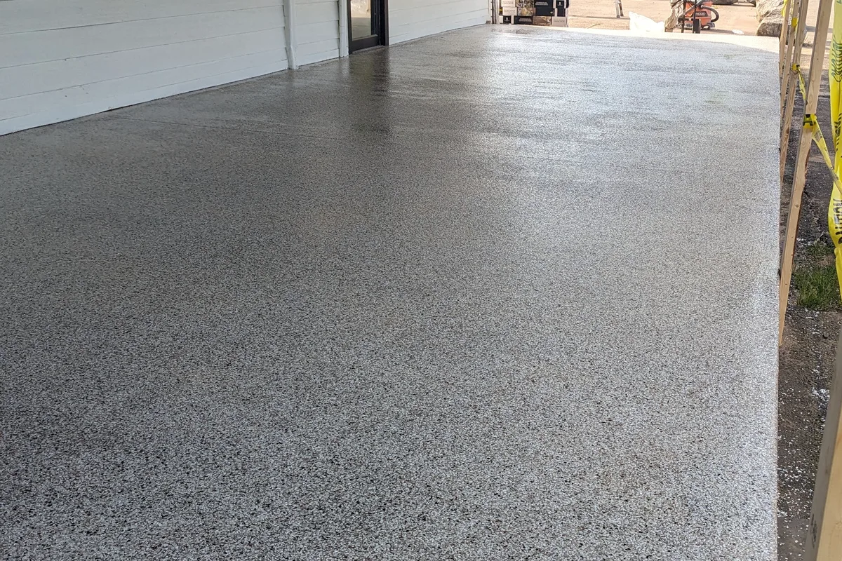 A flake floor on a covered outdoor walkway, open along one side to daylight.