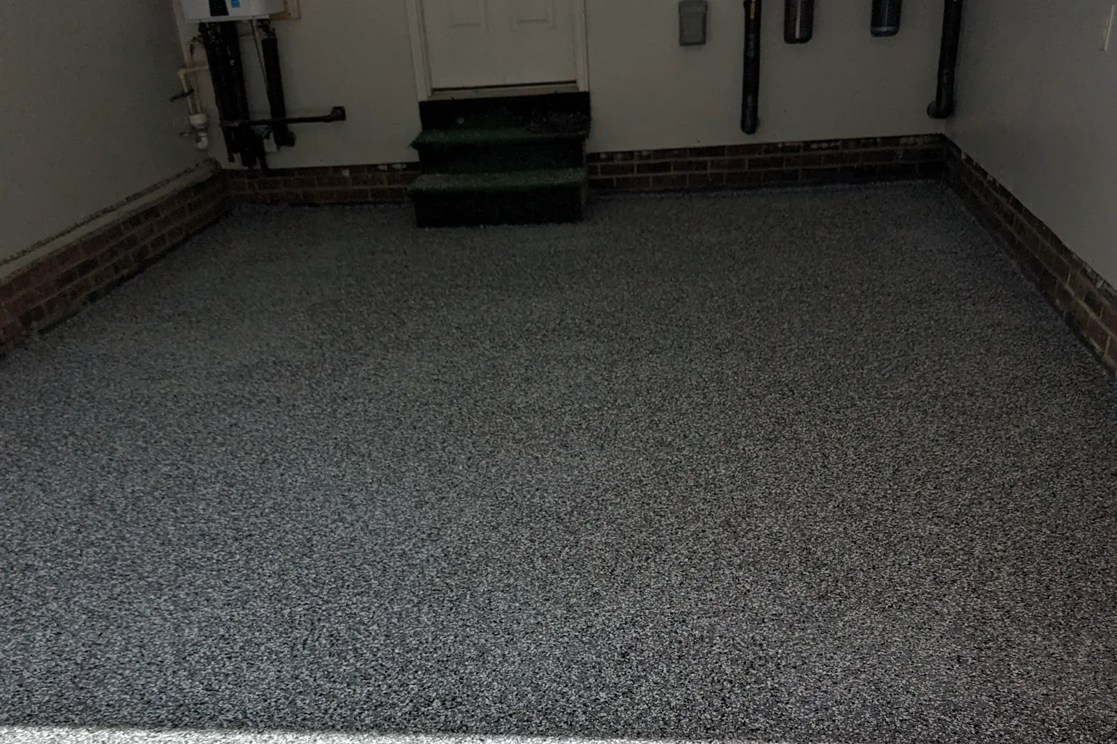 The same garage after installation, finished with a gray flake floor carried up to the brick knee wall.