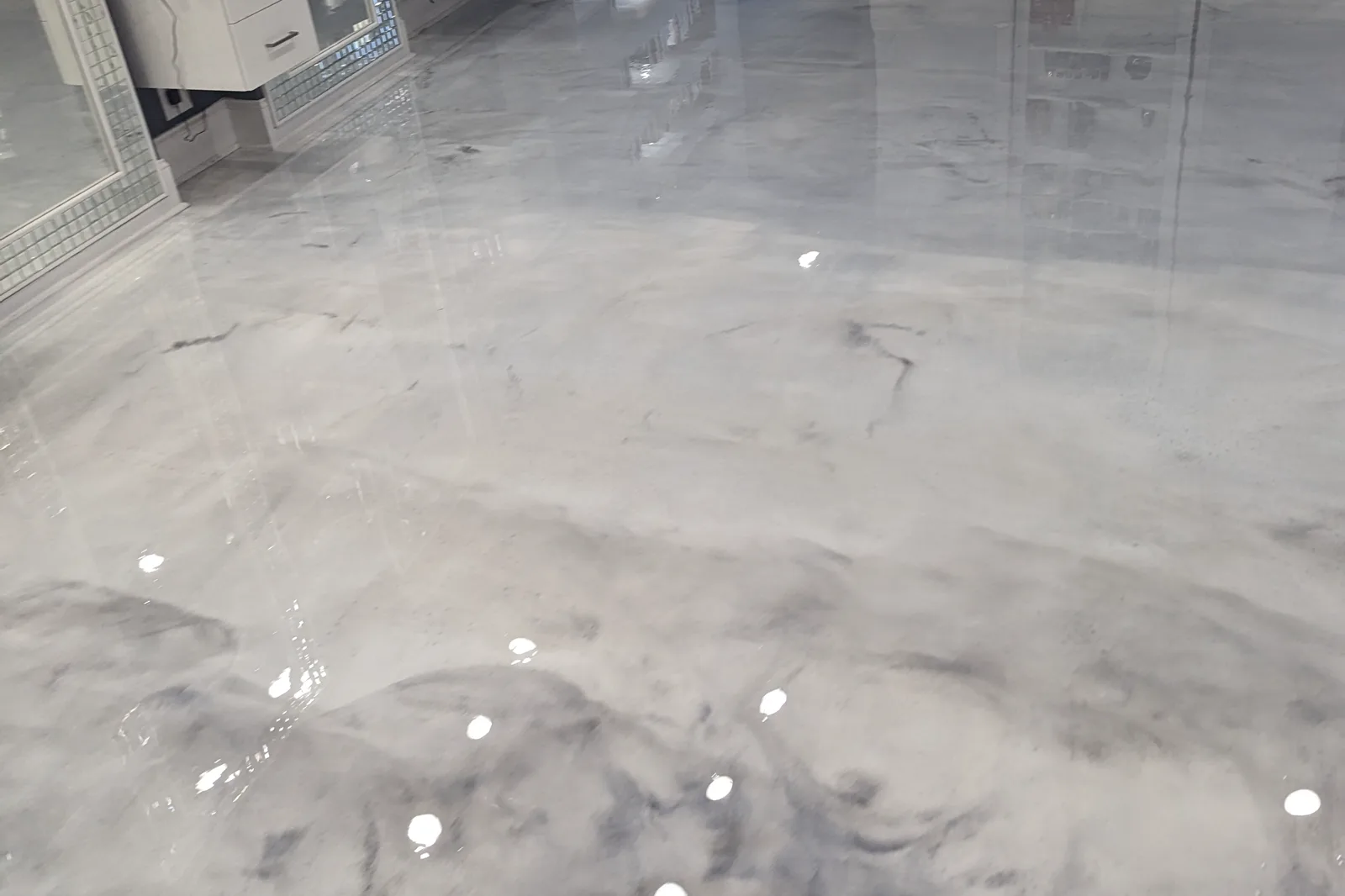 A high-gloss metallic floor reflecting ceiling lights and cabinetry, the surface acting almost as a mirror.