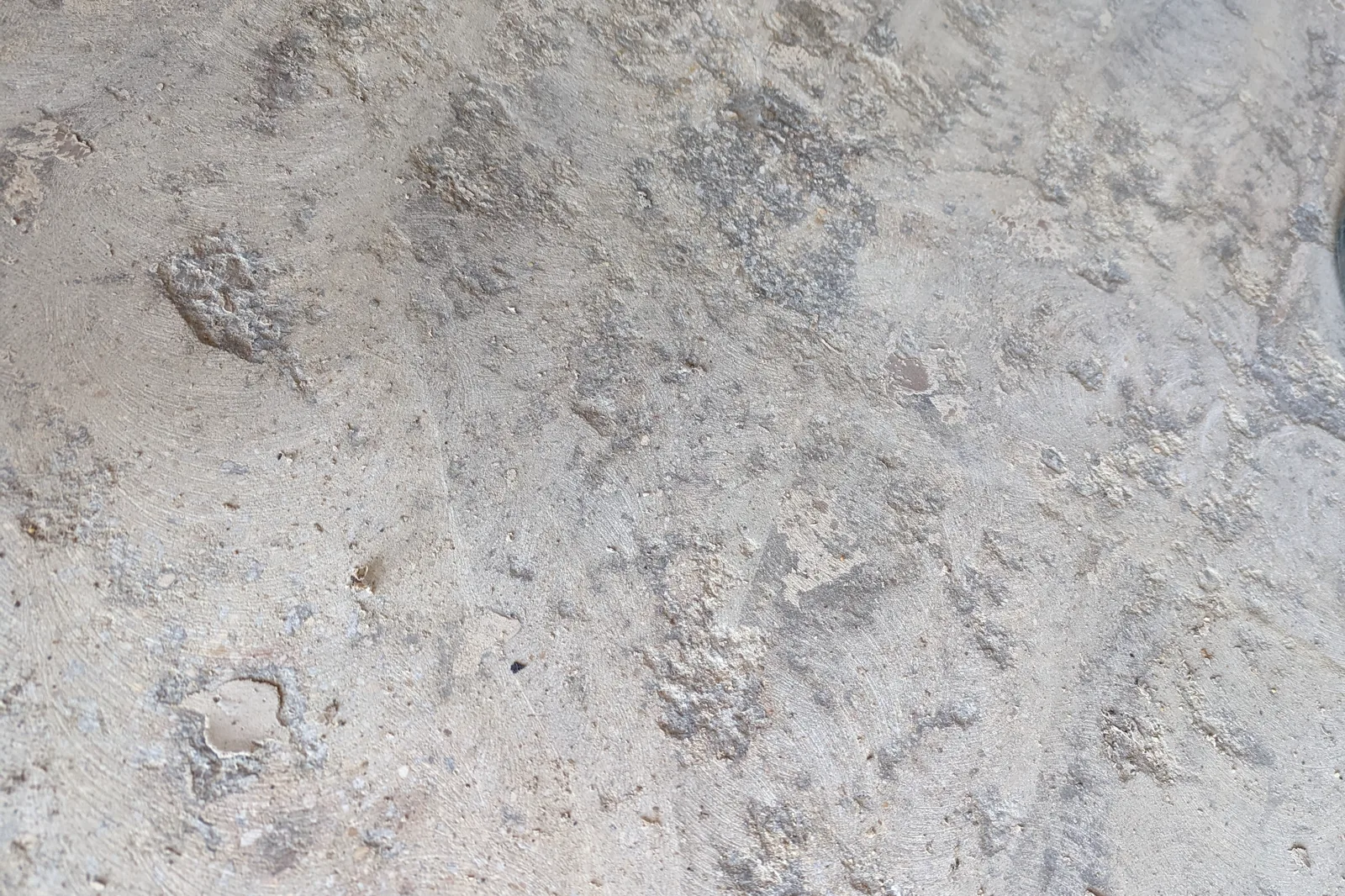 Close view of concrete after mechanical preparation, showing an open textured surface with exposed aggregate and small surface voids rather than a smooth finish.