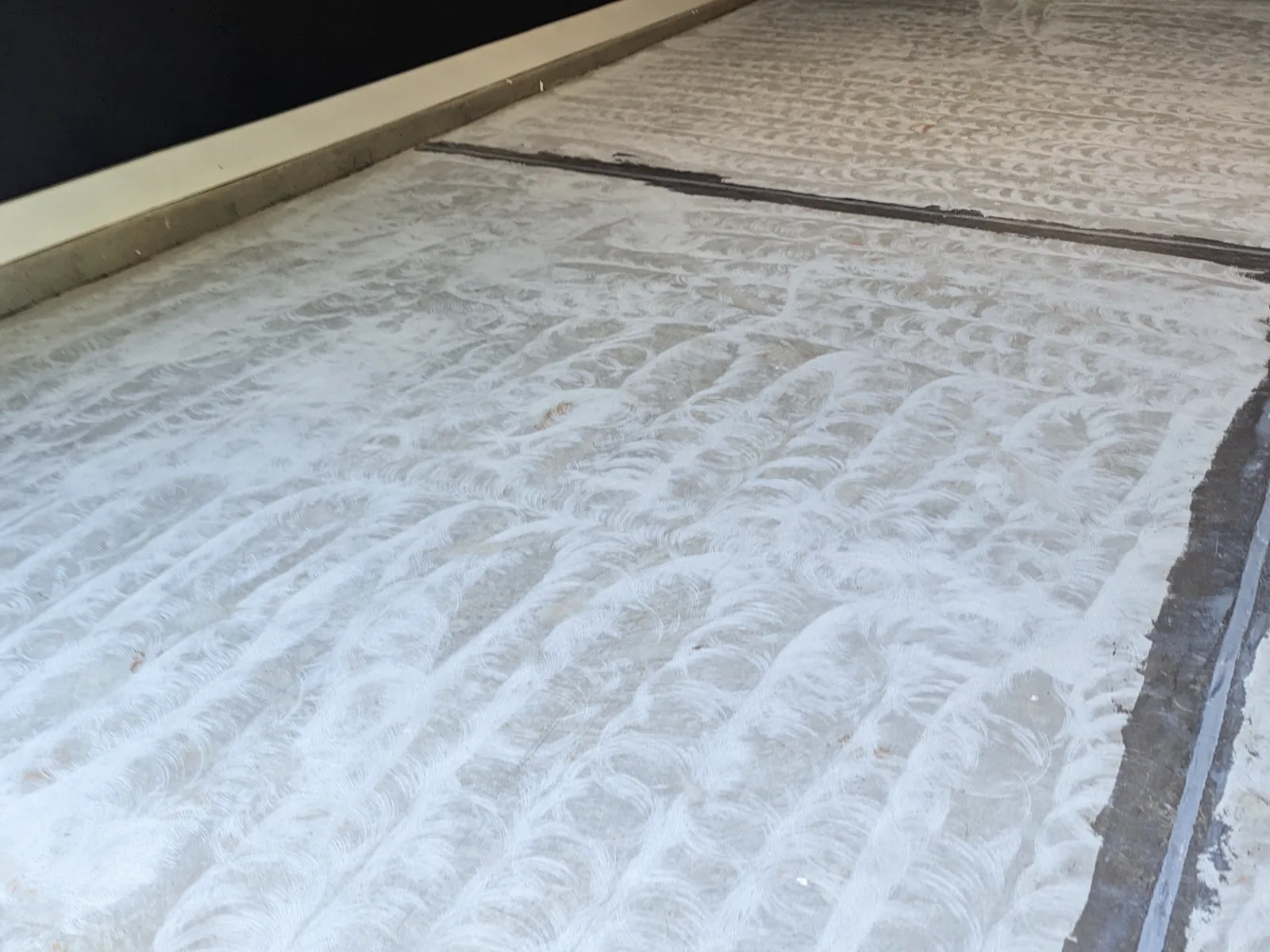 A concrete slab after grinding, showing overlapping circular marks across the whole floor